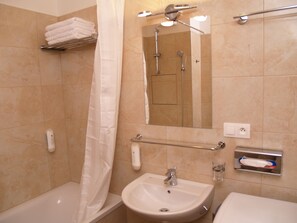 A bathroom with a bathtub, a sink, a mirror, and a towel rack.