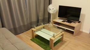 A modern living room with a glass-top coffee table, a flat-screen TV on a wooden stand, and a grey sofa. - Quality Apartment Miletičova (Bratislava)