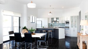 Une cuisine moderne avec un îlot central, des chaises noires et une table à manger.