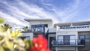 Un immeuble moderne à plusieurs étages, doté de balcons et d’une enseigne indiquant « MOLLYMOOK BEACHFRONT APARTMENTS ».