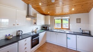 A modern kitchen with white cabinets, a black countertop, and a wooden ceiling. - Woodpecker Lodge With Hot Tub Near Cupar, Fife (Cupar)