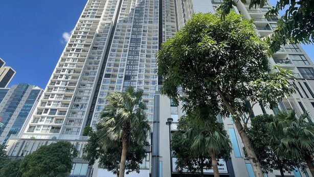 Un edificio alto con varios pisos, rodeado de vegetación y un cielo azul despejado.