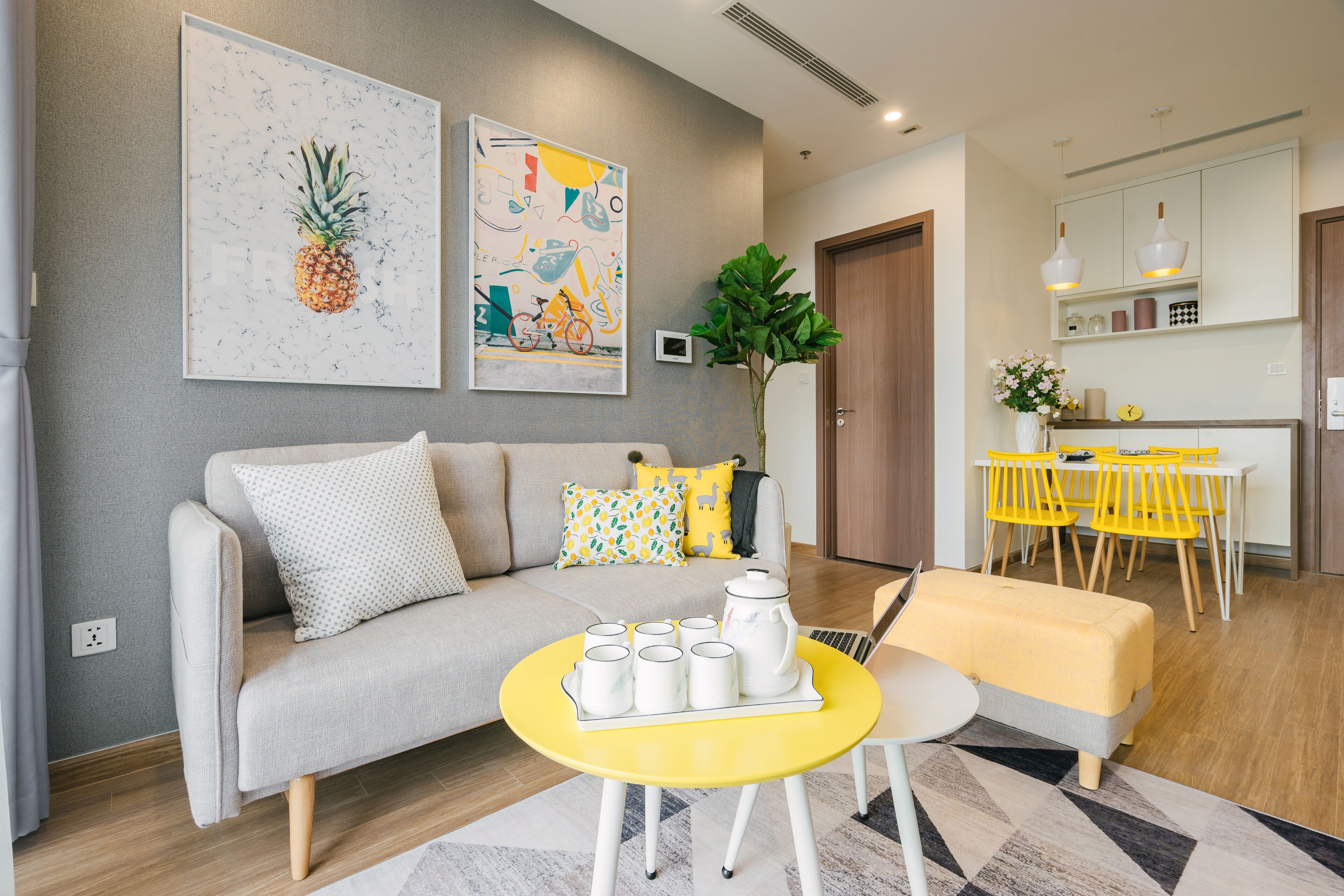 Un salon moderne avec un canapé, une table basse jaune et un coin repas avec des chaises jaunes.