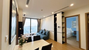 Una habitación de hotel moderna con un ventanal grande, un sofá, una mesa de comedor y una pequeña cocina.