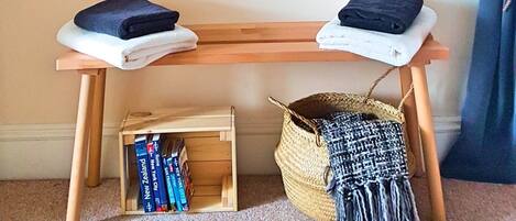 Une pièce comprenant un banc en bois, un tableau représentant un cerf, une petite bibliothèque et un panier en osier.