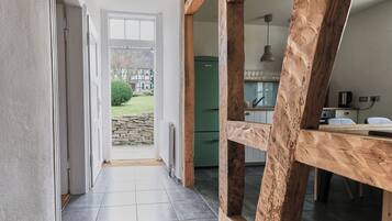 A hallway leading to a kitchen with a stone wall and a view of a house.