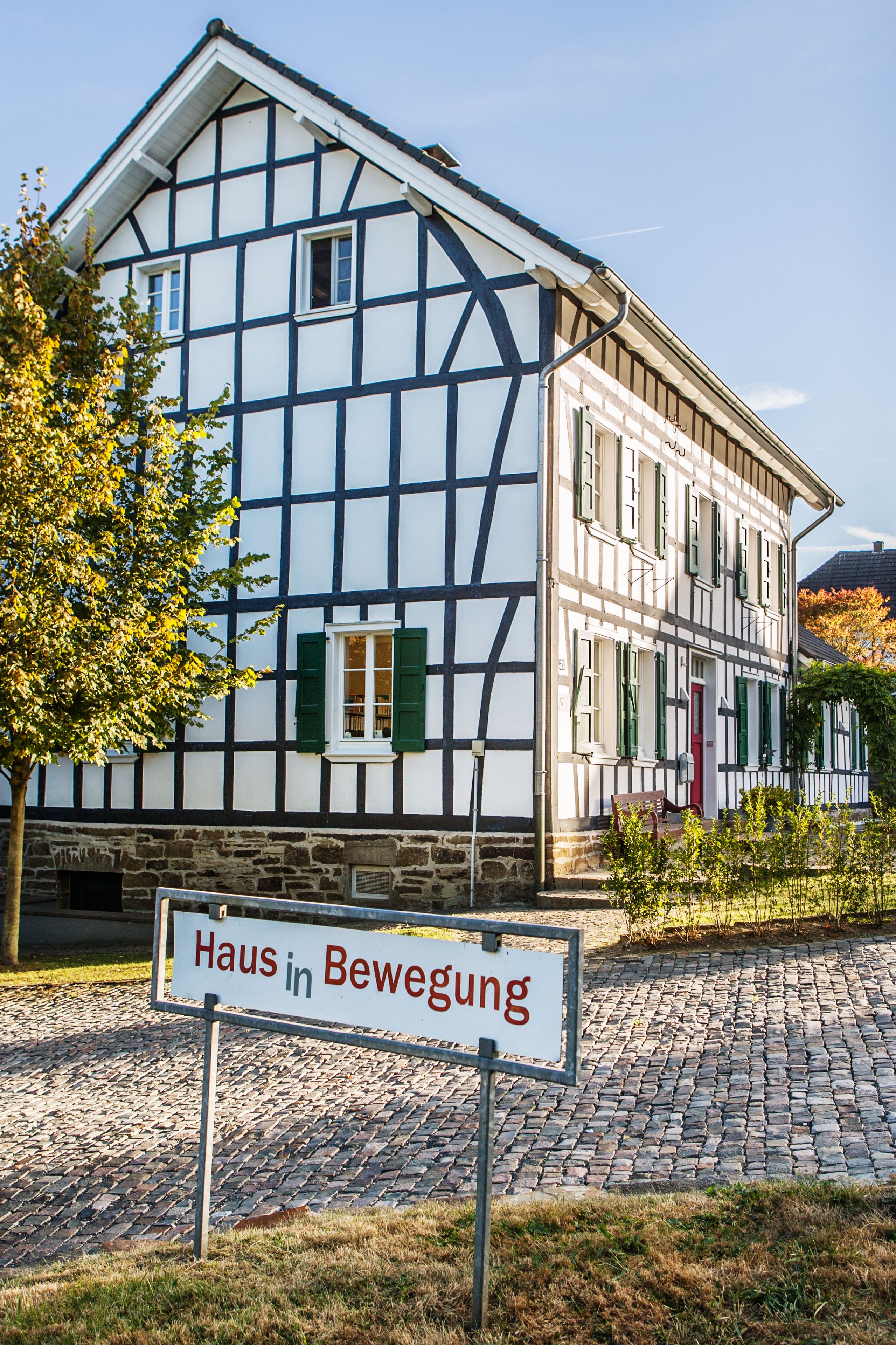 A traditional half-timbered house with a sign reading "Haus in Bewegung".