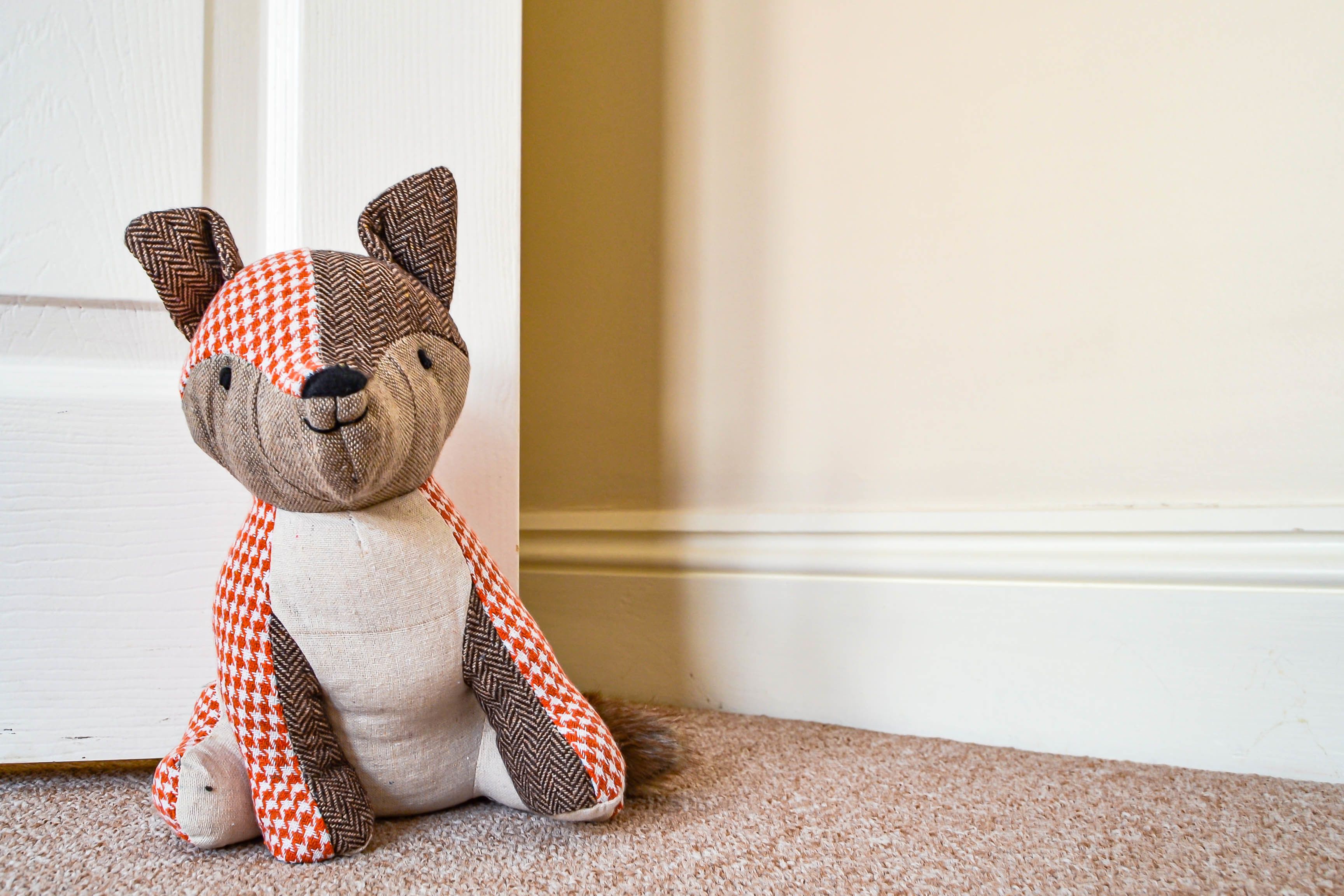 A plush toy with a checkered pattern sitting on a carpeted floor.