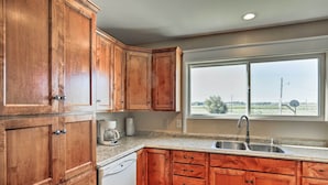 A kitchen with wooden cabinets, a dishwasher, and a window with a view of the countryside. - Wyoming Farmhouse Retreat! 10 Mi to Bighorn Canyon (Lovell)