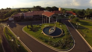 An aerial view of a landscaped area with a roundabout, a fountain, and buildings with red roofs. - Paradise Inn Hotel e Lazer (Catanduva)