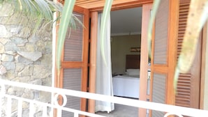 A balcony with a stone wall, wooden shutters, and a bed with white bedding. - Paradise Inn Hotel e Lazer (Catanduva)