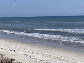 A beach with waves approaching the shore, sandy beach, and a clear sky.