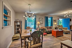 Een ruime woonkamer met een eethoek, een zithoek en een kroonluchter.