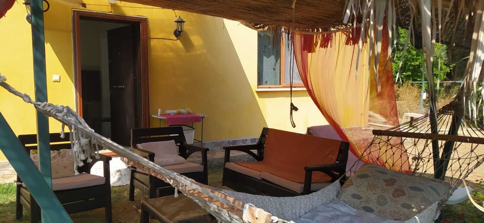 Un espace extérieur abrité, aménagé avec un hamac, une table et deux chaises.