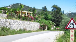 Un camino rural con un muro de piedra y un edificio amarillo.