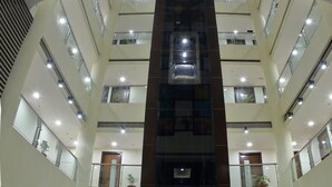 A multi-level atrium with a central staircase, glass railings, and potted plants. - Incredible One Hotel (Hyderabad)