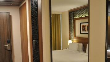A hotel room with a wooden bed, a large mirror, and a wooden wardrobe.