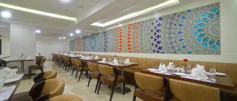 A dining area with long tables, chairs, and a decorative wall.