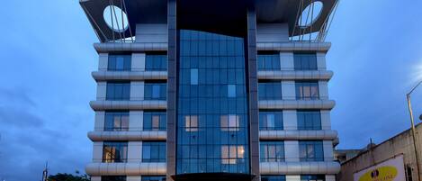 A modern hotel with a unique architectural design, featuring a curved facade and large windows.