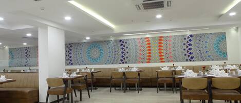 Interior moderno de restaurante con cabinas y mesas, decoración de pared con motivos y un ambiente limpio y bien iluminado.