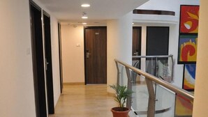 A corridor with a wooden floor, a potted plant, a glass railing, and a door with the number 502. - Incredible One Hotel (Hyderabad)