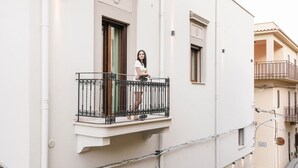 A balcony with a wrought iron railing, a window with a wooden frame, and a door.