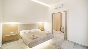 A modern hotel room with a bed, bedside table, and a mirror.