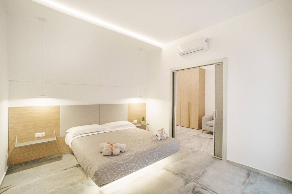A modern hotel room with a bed, bedside table, and a mirror.