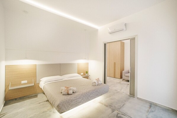 Una habitación de hotel moderna con cama, mesita de noche y espejo.