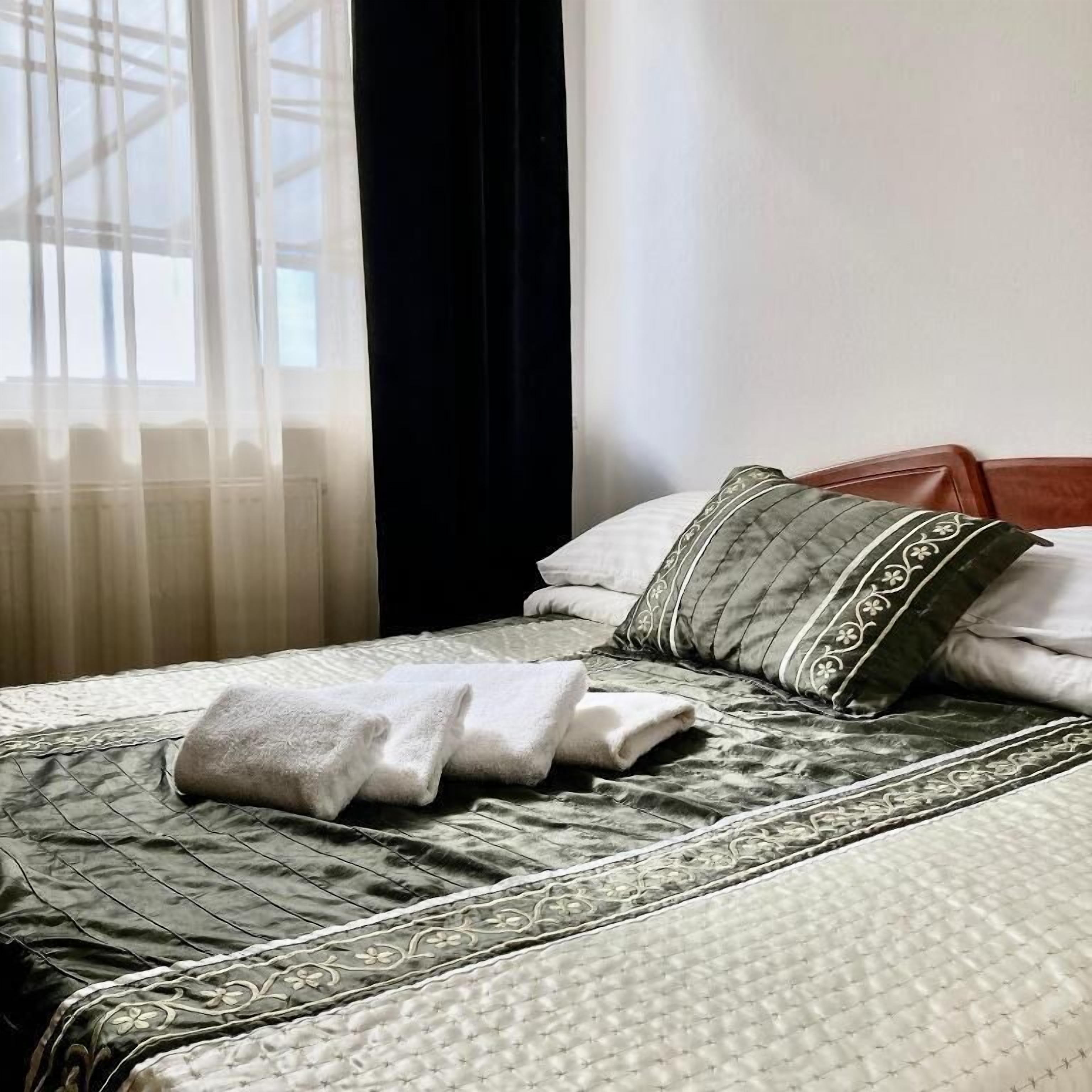 Una cama bien hecha con una colcha acolchada, dos almohadas y una toalla doblada.