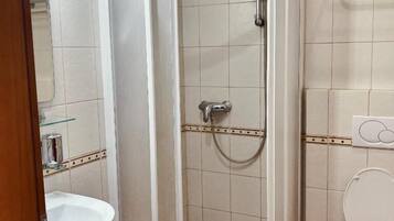 Un baño con ducha de vidrio, lavamanos e inodoro.