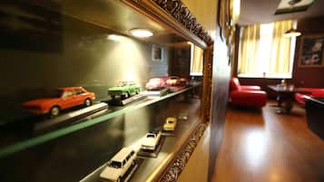 A room with a display of model cars in a glass case, a red couch, and a wooden floor.