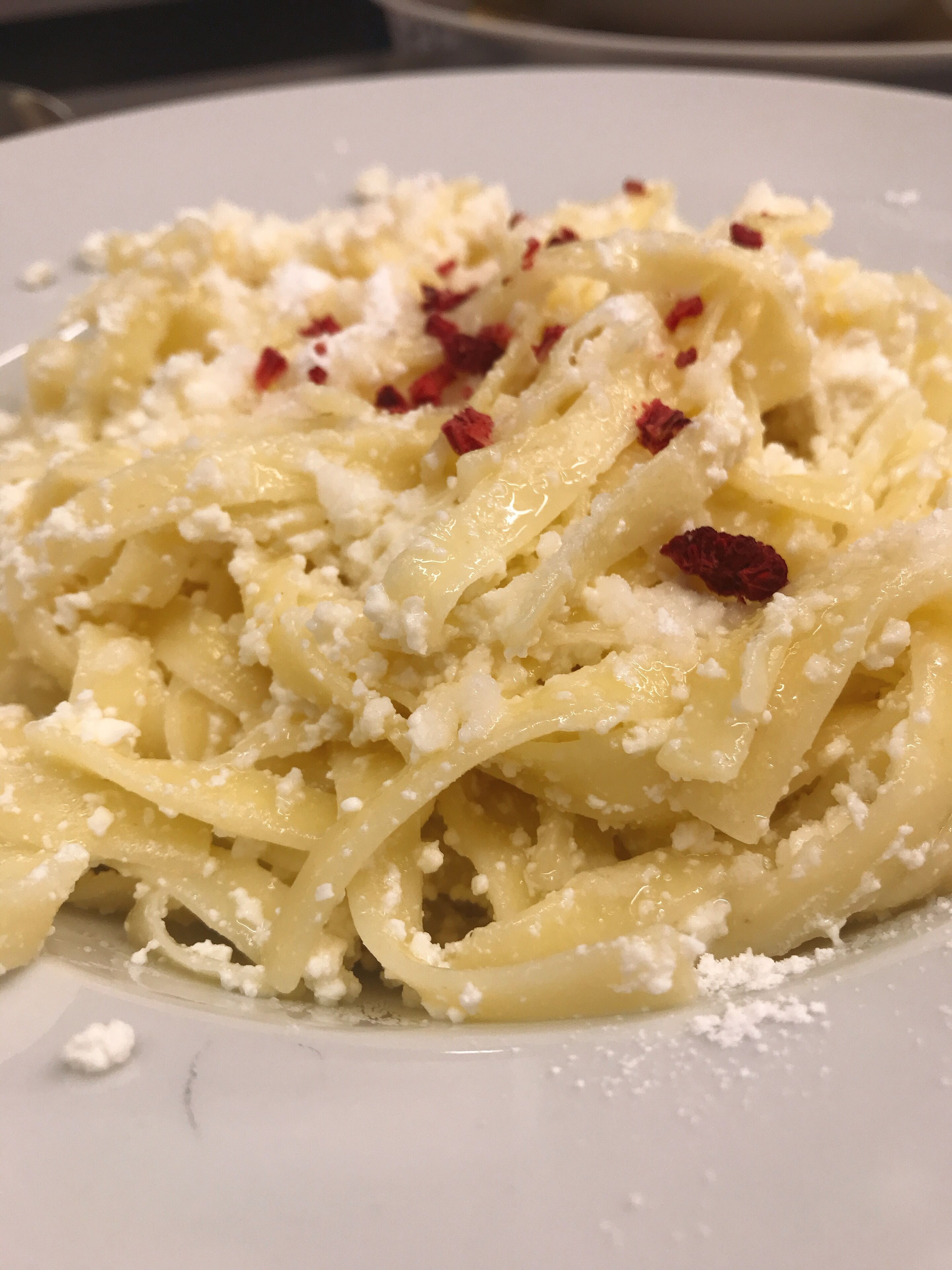 Une assiette de pâtes, de fromage et de flocons de piment rouge.