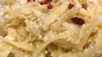 Une assiette de pâtes, de fromage et de flocons de piment rouge.