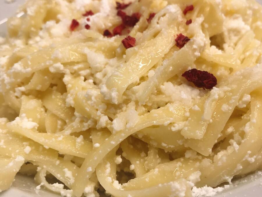 Une assiette de pâtes, de fromage et de flocons de piment rouge.