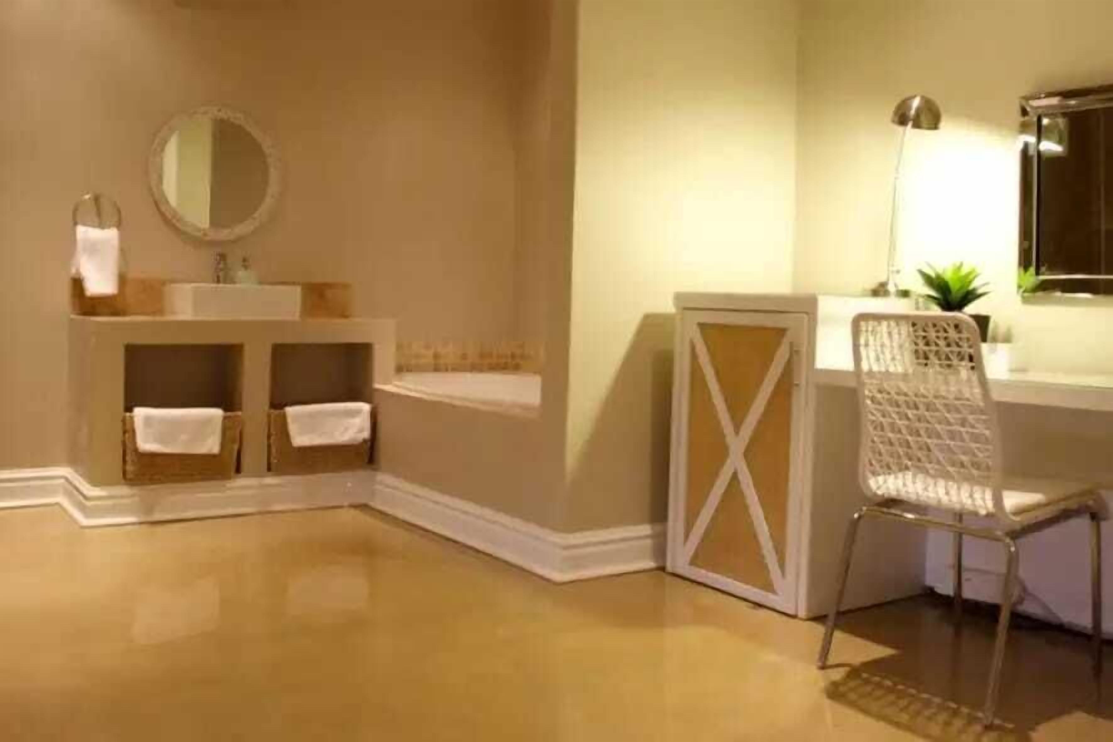 A bathroom with a sink, mirror, and chair.