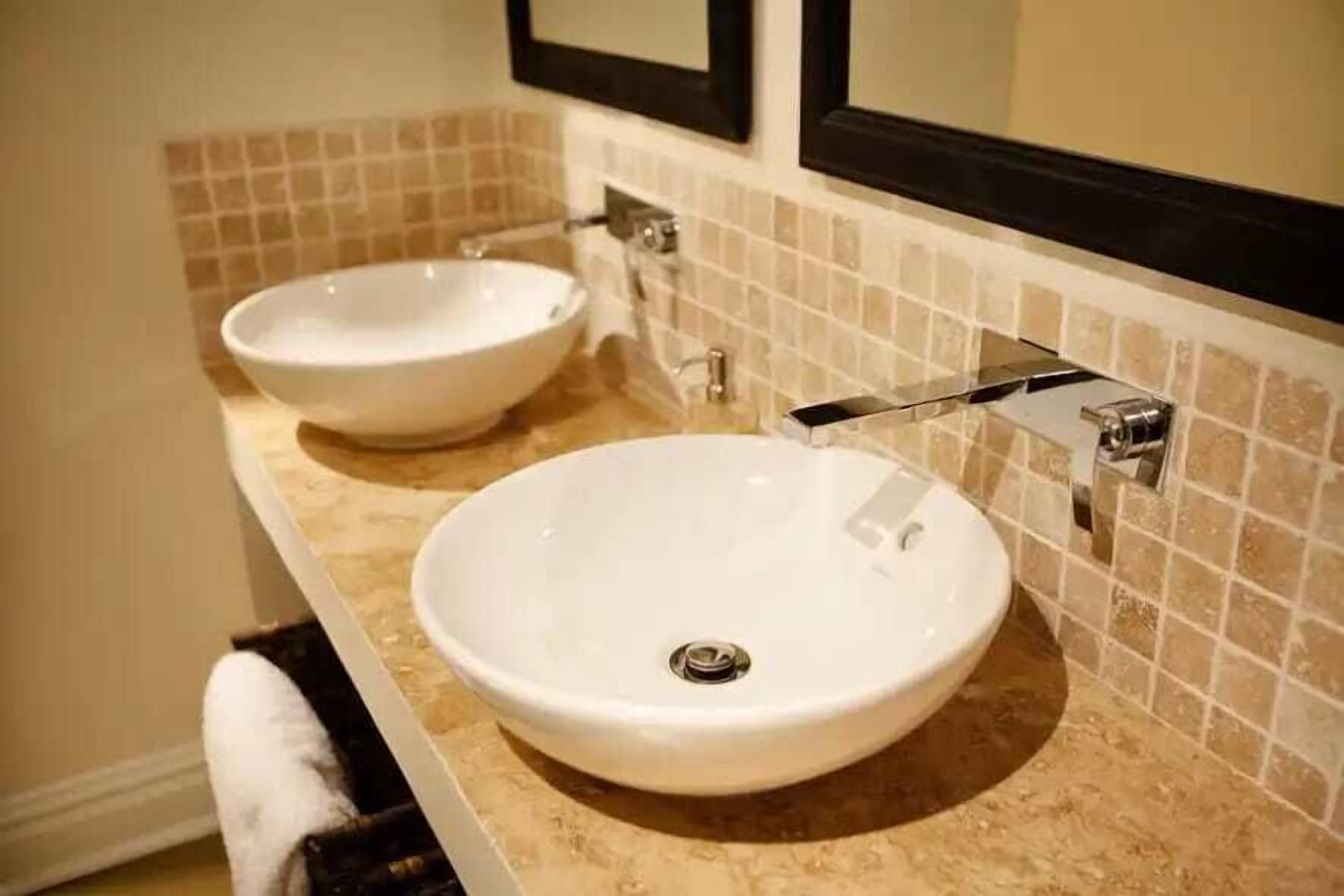 A bathroom with two round white sinks, a towel rack, and a mirror above the sink.