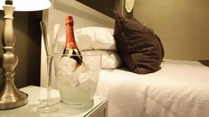 Een bed met een kussen, een fles champagne en een glas champagne in een ijskoeler.
