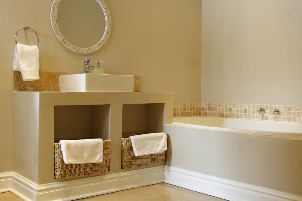 A bathroom with a sink, mirror, and bathtub.