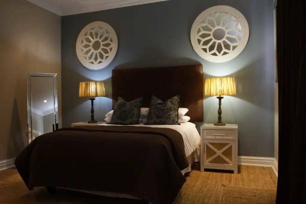 A bedroom with a large bed, two bedside tables with lamps, and decorative wall sconces.
