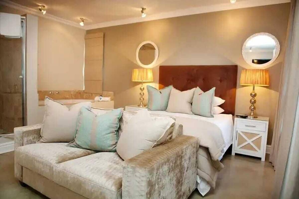 Ein Schlafzimmer mit einem Bett, einem Nachttisch, einer Couch und zwei Wandleuchten.