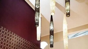 Een modern interieur met een patroon op de muur, een ronde spiegel, een tafel met een uniek ontwerp en hangende lampen.