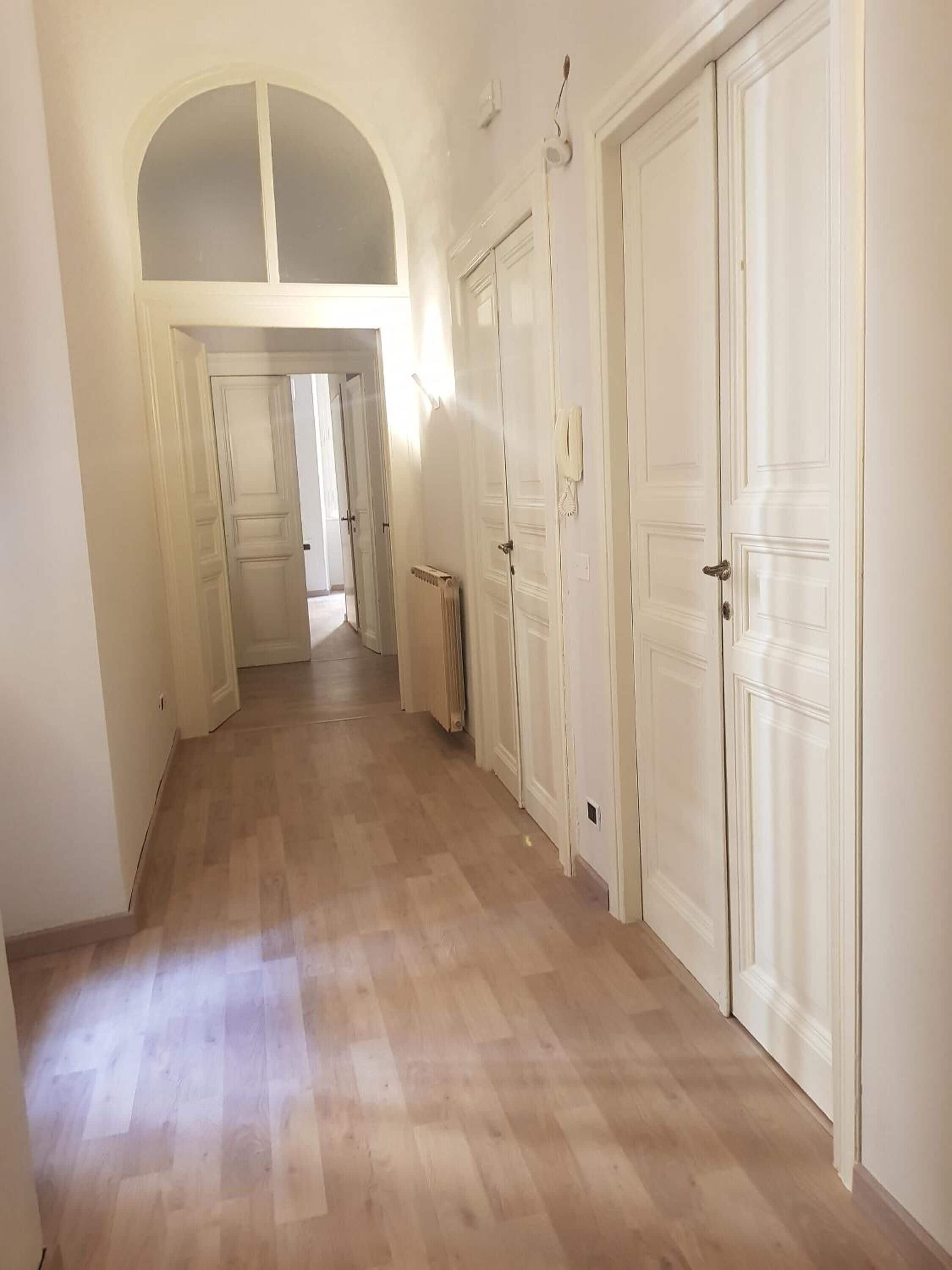 Käytävä, jossa on puulattia, valkoiset ovet ja patteri.