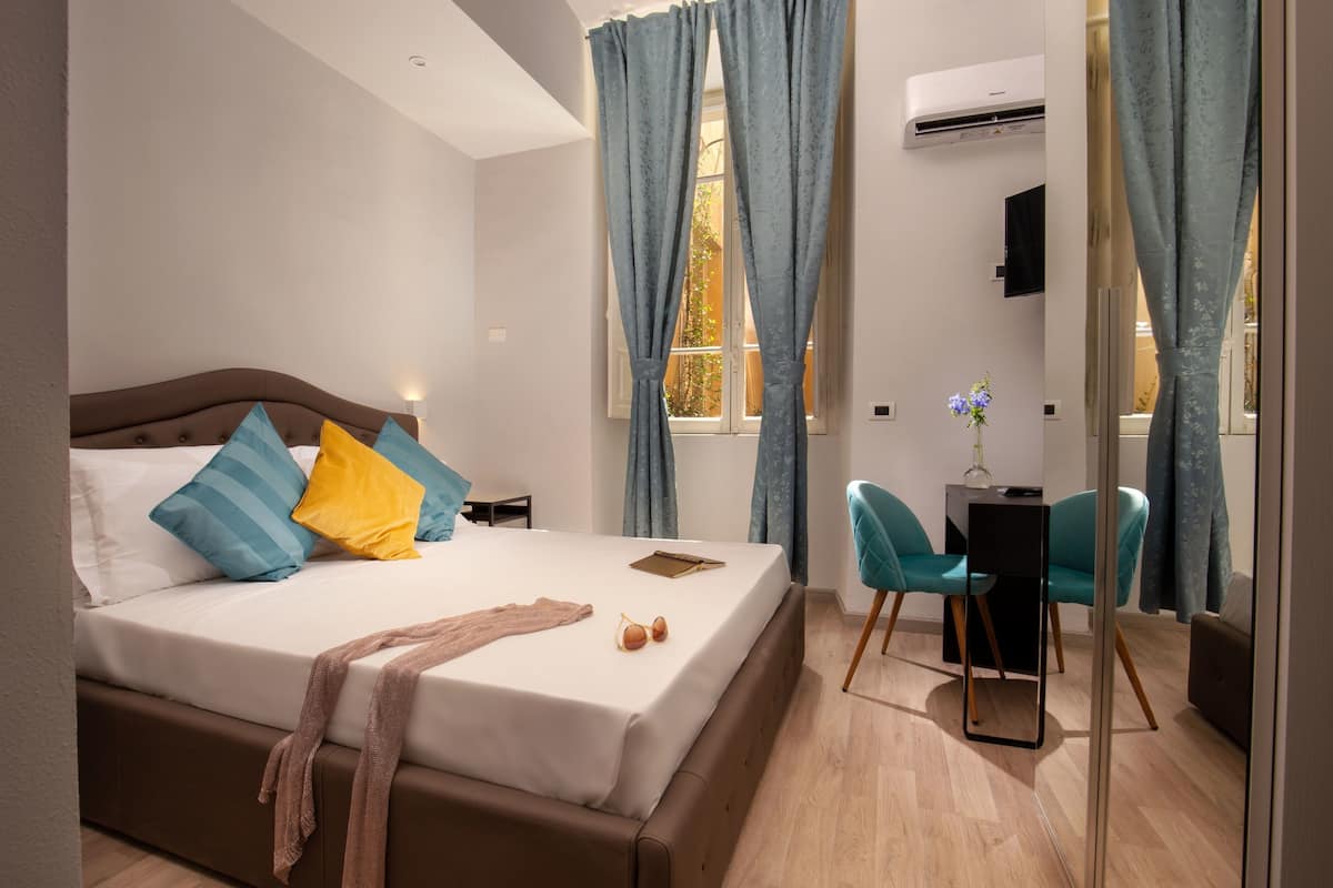 A modern hotel room with a large bed, a desk, and a chair.