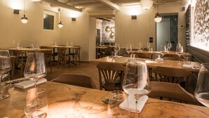 A restaurant interior with wooden tables and chairs, hanging pendant lights, and a marble countertop. - Cà Toresele Relais Osteria Garden (Verona)