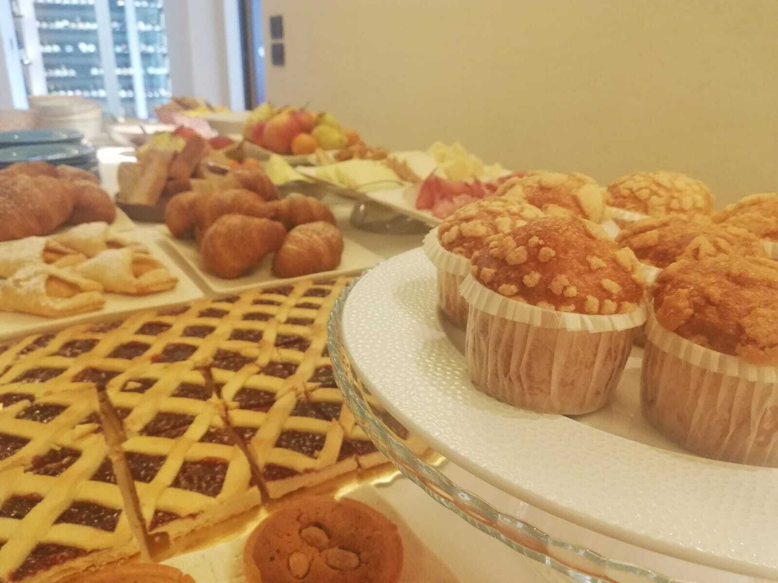 Une variété de produits de boulangerie, notamment des tartes, des muffins et des biscuits, présentés sur un plateau de service en verre.