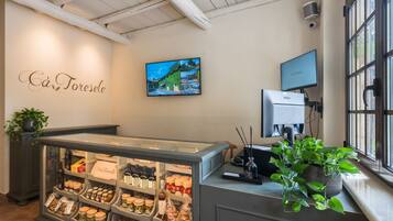 A bakery display with various baked goods and a wall-mounted television.