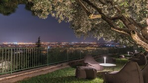 An outdoor seating area with a view of a cityscape at night. - Cà Toresele Relais Osteria Garden (Verona)