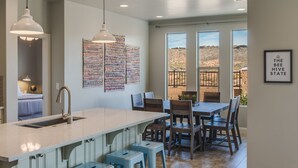 Cocina con una isla grande, luces colgantes y vistas al desierto a través de amplias ventanas.