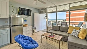 Un apartamento moderno con kitchenette, un sofá, una mesa de centro y un balcón con vista a la playa.